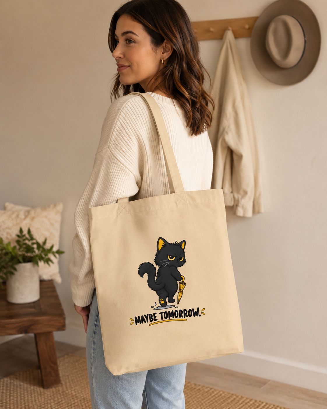 Woman carrying Oyster black cat tote bag showing the Maybe Tomorrow back design